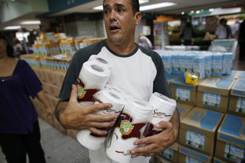 A man carries toilet paper at a supermarket in Caracas